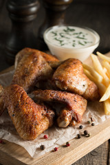 Barbecue grilled chicken wings close up with fries, tomato ketchup sauce and beer on wooden background. Meat food concept. 