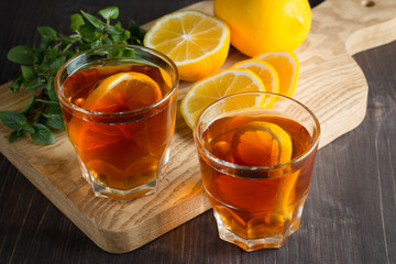 Glasses of cold ice tea with lemon, ice, mint on background. Homemade lemonade. Spring and summer drinks and beverages concept. 