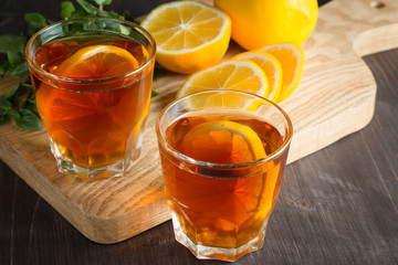 Glasses of cold ice tea with lemon, ice, mint on background. Homemade lemonade. Spring and summer drinks and beverages concept. 