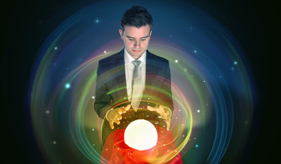 Young handsome man looking to the future of the universe in a crystal ball
