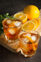 Glasses of cold ice tea with lemon, ice, mint on background. Homemade lemonade. Spring and summer drinks and beverages concept. 