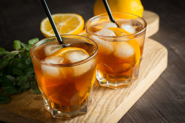 Glasses of cold ice tea with lemon, ice, mint on background. Homemade lemonade. Spring and summer drinks and beverages concept. 