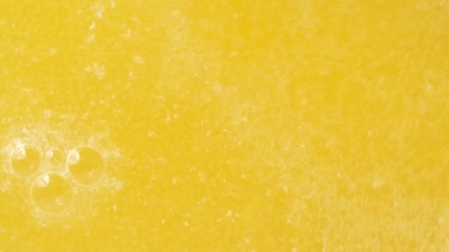 Closeup Shot of bubbles forming and fizzing from orange water.