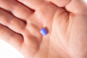 Top view of a caucasian hand with one blue MDMA, Amphetamine, Army Skull, Ecstasy, XTC pill.