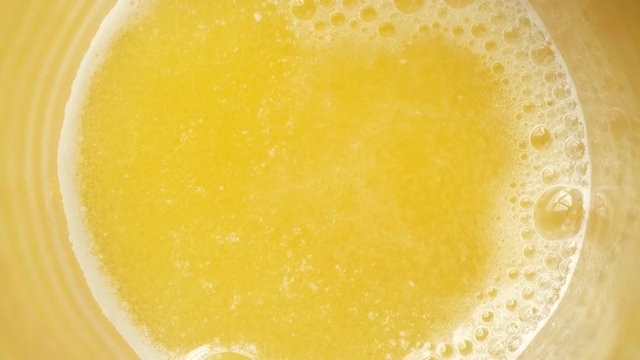 Closeup Shot of Aspirin dissolving in water. Bubbles forming in orange water.