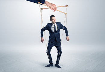 Puppet businessman in an empty room leaded by a huge hand
