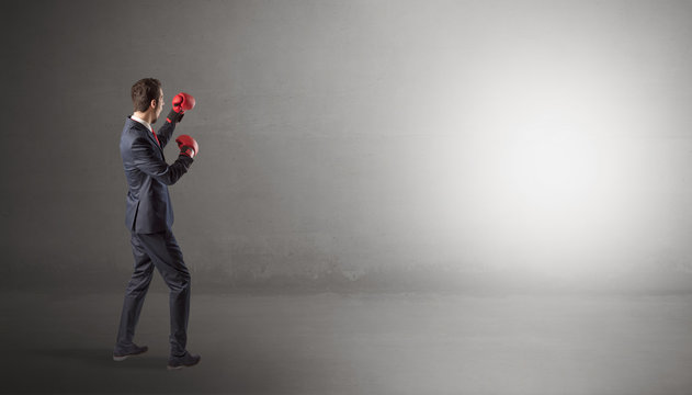 Businessman fighting with boxing gloves in an empty space
