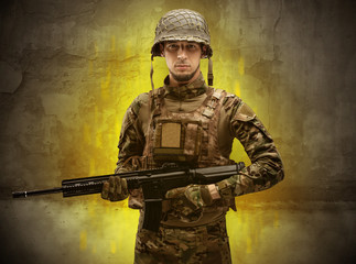 Fototapeta premium Hazard, menace soldier in a ruined crumbly building with arms on his hand 
