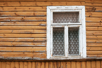 Fototapeta na wymiar Rustic window in wooden village cottage house. Grunge weathered, abandoned brown wood wall background.