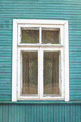 Rustic window in wooden village cottage house. Grunge weathered, abandoned blue paint wood wall background.