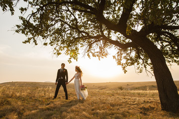 the bride and groom walk at sunset.