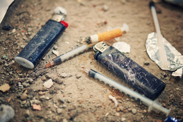 Used syringe on the ground - drugs Addiction equipment. Heroin, syringe, cigarette and lighter - drug addiction concept