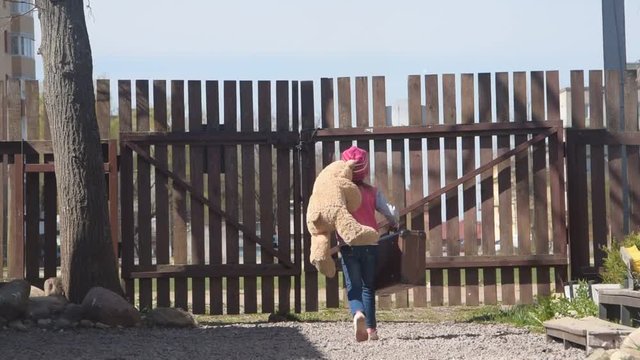the girl, a child climbed over the fence with a toy bear and a suitcase