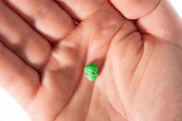 Top view of a caucasian hand with one green MDMA, Amphetamine, Army Skull, Ecstasy, XTC pill.