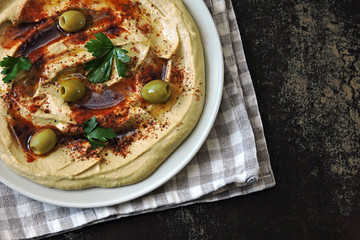 Hummus on a plate with paprika, olive oil and olives. Fresh homemade classic hummus. Middle Eastern cuisine.