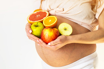 Pregnancy and healthy organic nutrition. Pregnant woman holds fresh vitamin fruits, free space. Place for text. Concept of expectation and health.