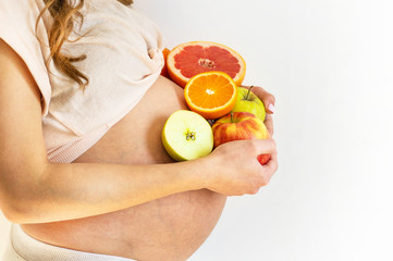 Pregnancy and healthy organic nutrition. Pregnant woman holds fresh vitamin fruits, free space....