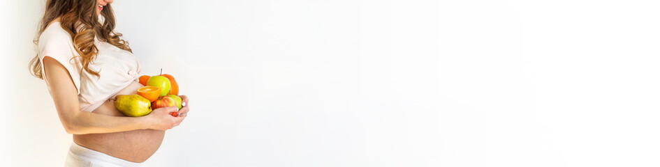 Pregnancy and healthy organic nutrition. Pregnant woman holds fresh vitamin fruits, free space. Place for text. Concept of expectation and health.