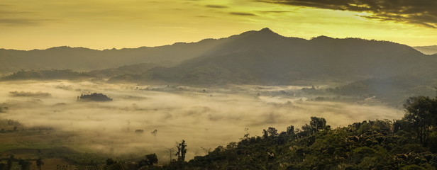 Mountain view morning sea of fog in valley around with forest and the hills with yellow sun light in the sky background, sunrise at Phu Langka Photo Corner View Point, Route 1148, Phayao, Thailand.
