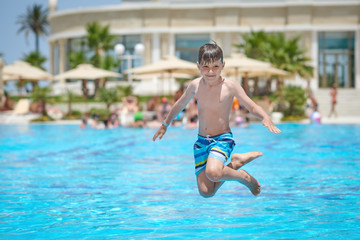 Naklejka premium Caucasian boy making jump into swimming pool water.