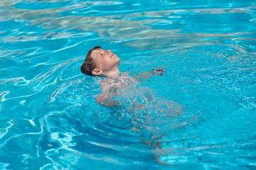 Learning to swim. Boy swimming along the side of pool.
