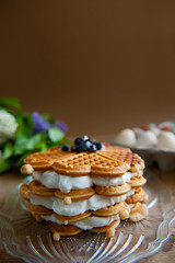Homemade waffles with aronia, eggs and lilac flowers on the wooden table