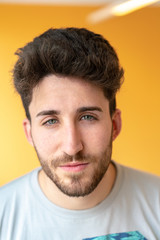 Obraz premium Close-up portrait of an attractive young man with green eyes staring with a yellow background