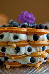 Homemade waffles with aronia, eggs and lilac flowers on the wooden table
