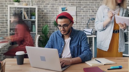 Time-lapse of busy guy using laptop in office while colleagues rushing around moving fast doing job. Rapid lifestyle, creative business and modern technology concept.
