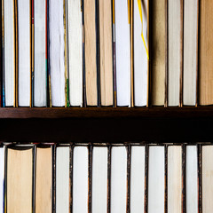 Lots of colourful thick open books stand on a dark background