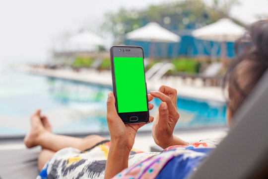 Picture of a woman relaxing by the pool. Her hands are touching the green phone screen. For the creators to put in additional images