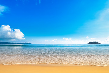 Wide beach with golden sand shore and blue sky
