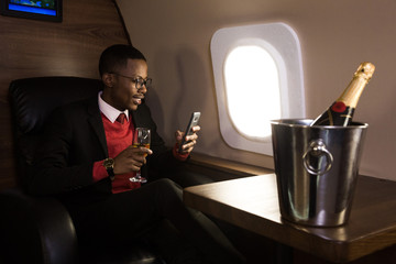 Successful young Afro American black businessman sitting in the chair of his private jet