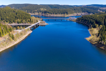 Obraz premium Aerial view of a flight over a reservoir in the Harz Mountains, a German low mountain range, with mountains and forests