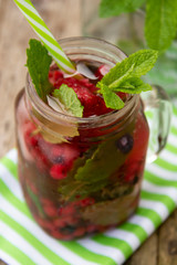 Stylish fresh ice, cold fruit tea background, Mason jar cup with straw, summer fruit tea drink, wooden background