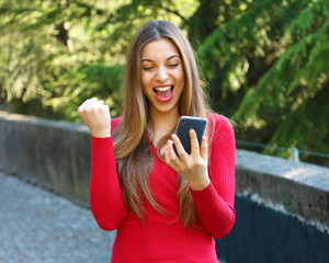 Euphoric woman watching her smart phone outdoor