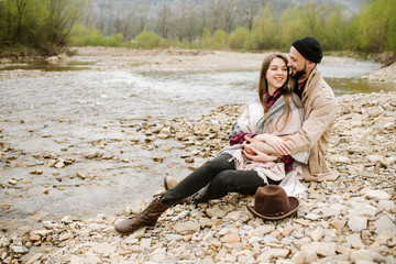 Young travelers couple hugs each other on the mountain river on the background