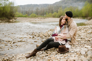Young travelers couple hugs each other on the mountain river on the background