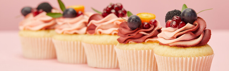panoramic shot of sweet cupcakes with berries and fruits on pink surface