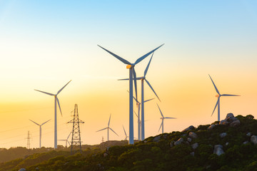 Wind turbines on the mountains are on the beach at sunrise and sunset.