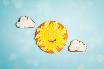 Homemade gingerbread sun and clouds on a blue background.