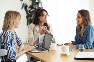 Three business colleagues working together in modern workspace. Brainstorming concept.