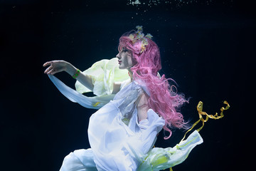 woman with pink hair in white dress underwater. Mermaid, nymph or drowning in white dress under water