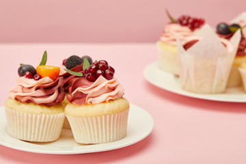 two plates with sweet cakes on pink surface