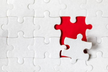 Obraz premium Unfinished white jigsaw puzzle pieces. Fill in pieces of the jigsaw puzzle. Complete the jigsaw puzzle with the missing pieces. Fragment of a folded white jigsaw puzzle.