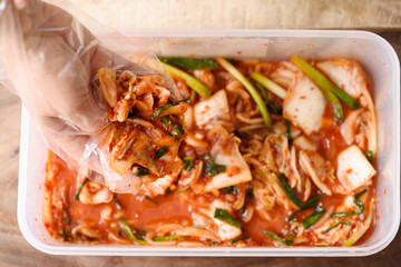 Kimchi cabbage in the plastic box with hand, Korean food
