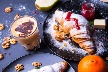 Delicious breakfast with fresh croissants and coffee served with butter and honey.