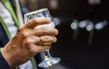 man's hand holds a glass of beer in bar