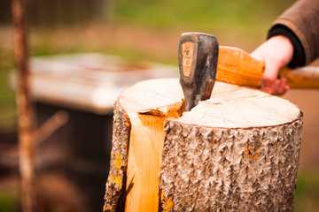 Man chops wood with an ax. Bonfire background. Close up.
