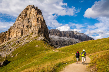 Fototapeta na wymiar Active senior caucasian couple hiking in mountains with backpacks, enjoying their adventure. Location: Dolomites Alps, South Tyrol, Italy, Europe.